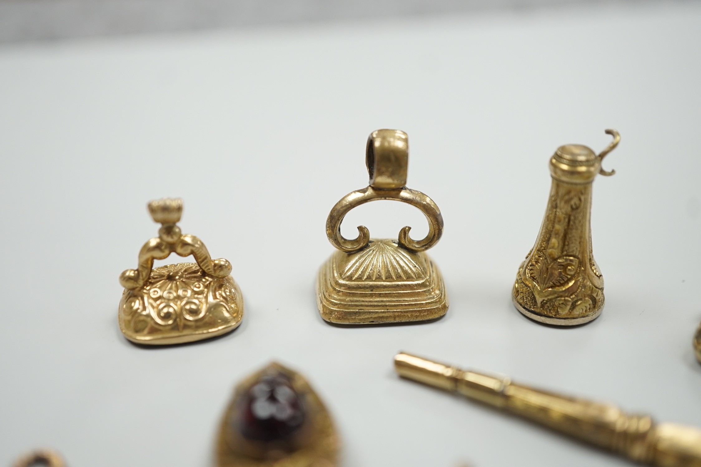 Four assorted 19th century and later yellow metal overlaid and gem set fob seals, a Victorian 15ct gold and sardonyx spinning fob, a sardonyx set locket, damaged pendant and yellow metal and two stone set watch key.